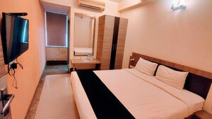 A hotel room with a large bed, a TV, a mirror, and an air conditioning unit. - Hotel Apex Intercontinental (Jaipur)