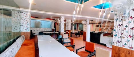 Un restaurante moderno con mesas largas compartidas, cabinas individuales y una zona de bar.