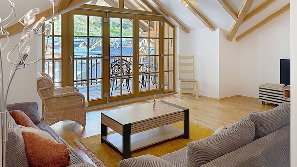 A spacious loft with high ceilings, large windows, and a view of a residential area. - Beautiful apartment for 4 guests with pool, WIFI, TV and terrace (Rauris)
