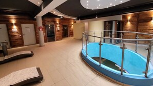 A modern indoor pool area with a glass railing, wooden walls, and a tiled floor. - Nice apartment for 6 people with WIFI, pool, TV and terrace (Rauris)