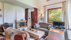 A cozy living room with a fireplace, a sofa, a TV, and a dining area.