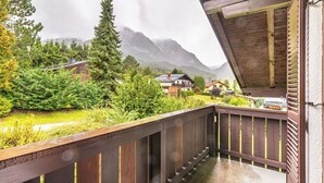 A wooden balcony with a view of a mountainous landscape and houses.