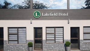 Een gebouw met een bord waarop 'Lakefield Hotel' staat en een parkeerplaats ervoor.