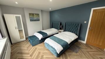 Quarto com duas camas, um guarda-roupa, um radiador e um quadro na parede.