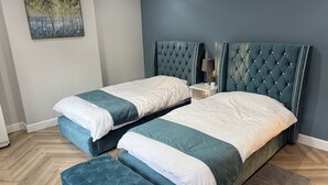 Un dormitorio con dos camas, una mesita de noche, una lámpara y un cuadro en la pared.