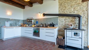 A kitchen with white cabinets, a stone wall, and a wood-burning stove. - Nice apartment for 4 guests with WIFI, terrace, pets allowed and panoramic view (Igliano)