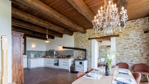 A spacious kitchen with modern appliances, a dining area with a table set for two, and a stone wall. - Nice apartment for 4 guests with WIFI, terrace, pets allowed and panoramic view (Igliano)