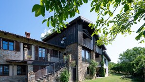 A two-story stone house with a balcony, a staircase, and a well-maintained lawn. - Nice apartment for 4 guests with WIFI, terrace, pets allowed and panoramic view (Igliano)