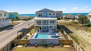 A two-story house with a balcony, a swimming pool, and a view of the beach.