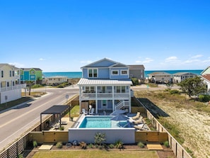 A two-story house with a balcony, a swimming pool, and a view of the beach.
