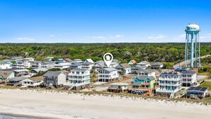 A coastal residential area with beachfront houses, a water tower, and a clear sky.