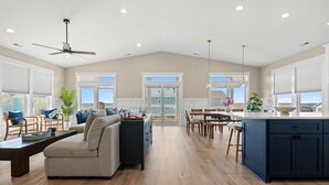 A spacious living room with a sofa, dining area, and kitchen island.