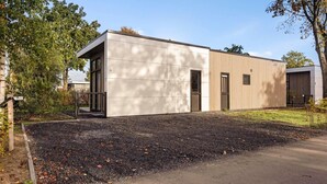 Een modern gebouw met een plat dak, grote ramen en een grindpad.