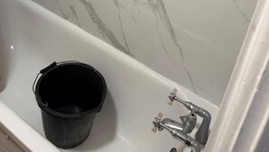 A bathroom with a white bathtub and marble walls. - 6 Guests - 3 Bedrooms - Close to London Center (London)