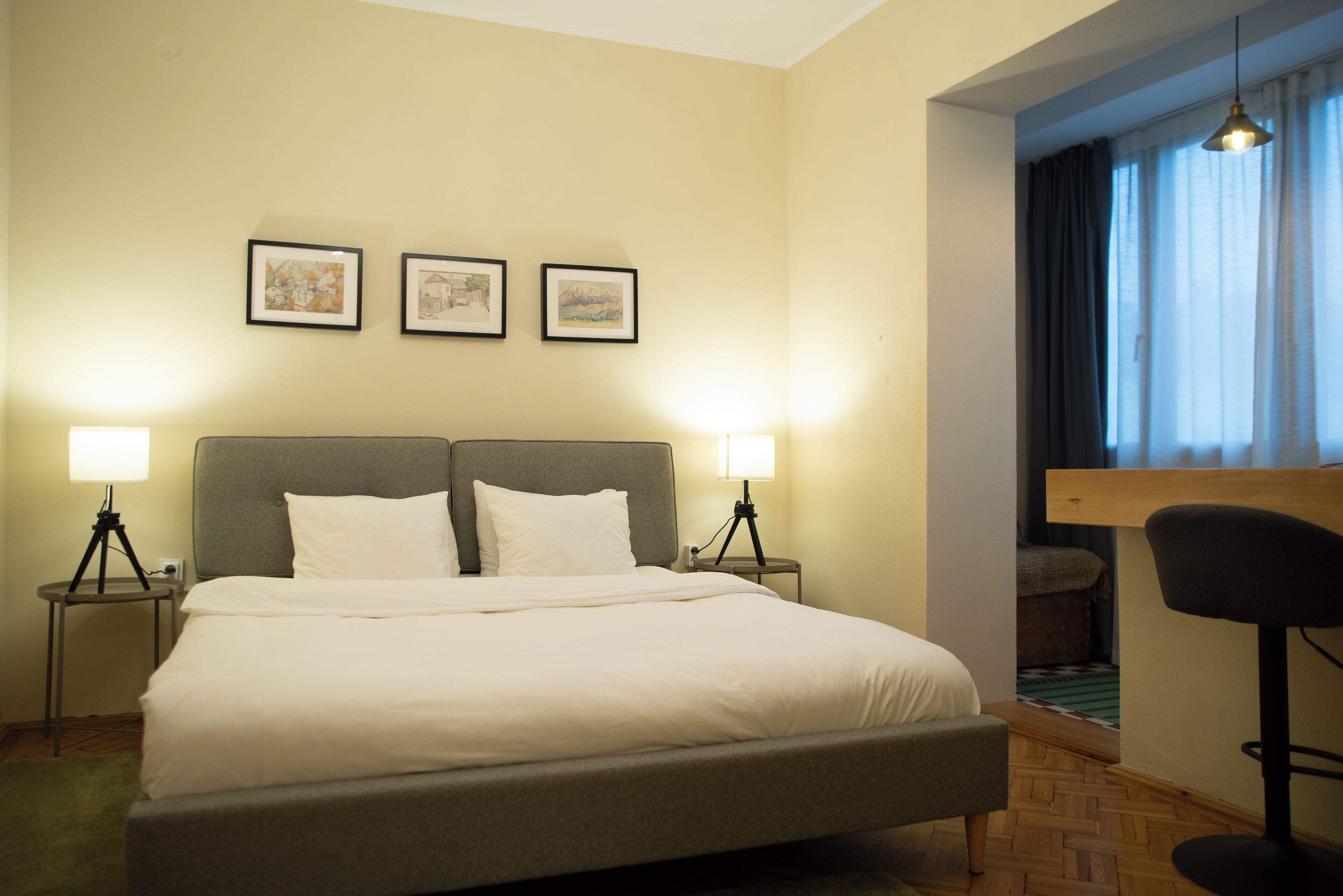 Une chambre d’hôtel avec un grand lit, deux lampes de chevet et trois tableaux encadrés au mur.
