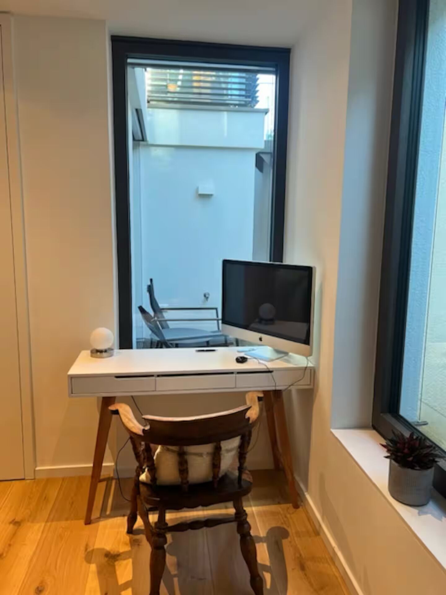 A corner room with a desk, chair, and a window with blinds.