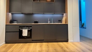 A modern kitchen with dark cabinets, a wooden countertop, and a built-in oven. - Apartment Ziegelhofring (Bad Vilbel)