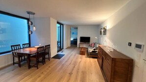 A modern living space with a wooden dining table, a sofa, and a TV. - Apartment Ziegelhofring (Bad Vilbel)