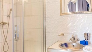A bathroom with a glass-enclosed shower, a sink with a mirror, and a towel rack. - Les portes de l'orient spa 1 Riad around the castles. (Tours)