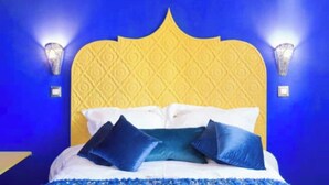 A bed with a yellow headboard, white bedding, and blue pillows. - Les portes de l'orient spa 1 Riad around the castles. (Tours)