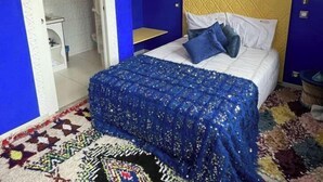 A bedroom with a blue and white color scheme, a bed with blue bedding, a decorative wall hanging, and a patterned rug. - Les portes de l'orient spa 1 Riad around the castles. (Tours)
