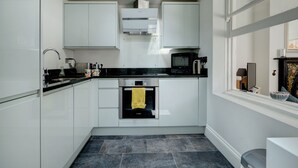 Een moderne keuken met witte kasten, een zwart aanrecht, een ingebouwde oven en een magnetron.