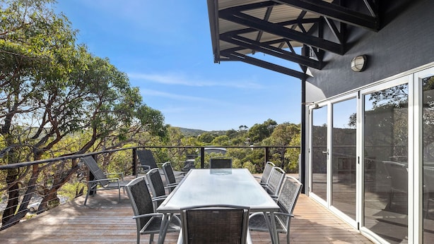 A deck with a table and chairs, overlooking a natural landscape. - Orchid Haven (Fairhaven)