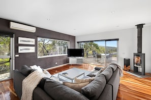 A modern living room with a large sofa, a flat-screen TV, and a fireplace.