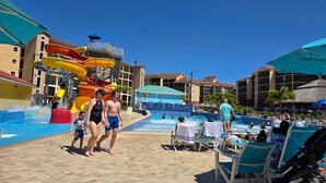 Un área de parque acuático con múltiples toboganes y una piscina, rodeada de edificios con balcones.