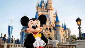 Mickey Mouse frente a una estructura que parece un castillo.