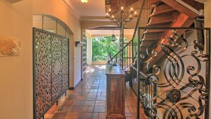 Una imponente escalera con barandales de metal ornamentados y un candelabro, que conduce a un nivel superior.