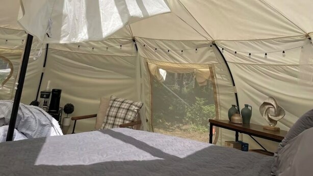 Uma tenda com cama, uma mesa pequena e uma janela.