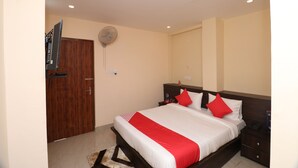 A neatly arranged bedroom with a bed, bedside tables, a TV, and a fan. - HOTEL O MDA INN (Lucknow)