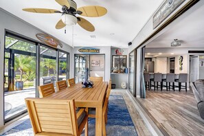 A spacious dining area with a large wooden table and chairs, a ceiling fan, and large windows offering a view of the outdoors. - ‼️Punta Gorda Paradise‼️| 3BR w/ Water Views, Pool (Punta Gorda)