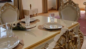 Une salle à manger avec des chaises décorées, une table dressée pour quatre personnes et une vue sur l’extérieur grâce à de grandes fenêtres.