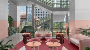 A modern indoor space with multiple tables and chairs, a staircase, and large windows. - Close to UT Austin + On-site Dining, Pool & Gym (Austin)