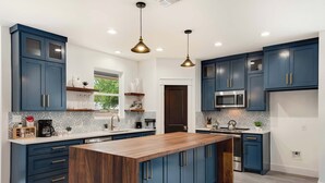 Una cocina moderna con armarios azules, una isla de madera y electrodomésticos de acero inoxidable.