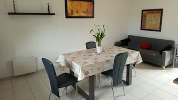 Een eetgedeelte met een tafel, stoelen, een potplant en twee banken.