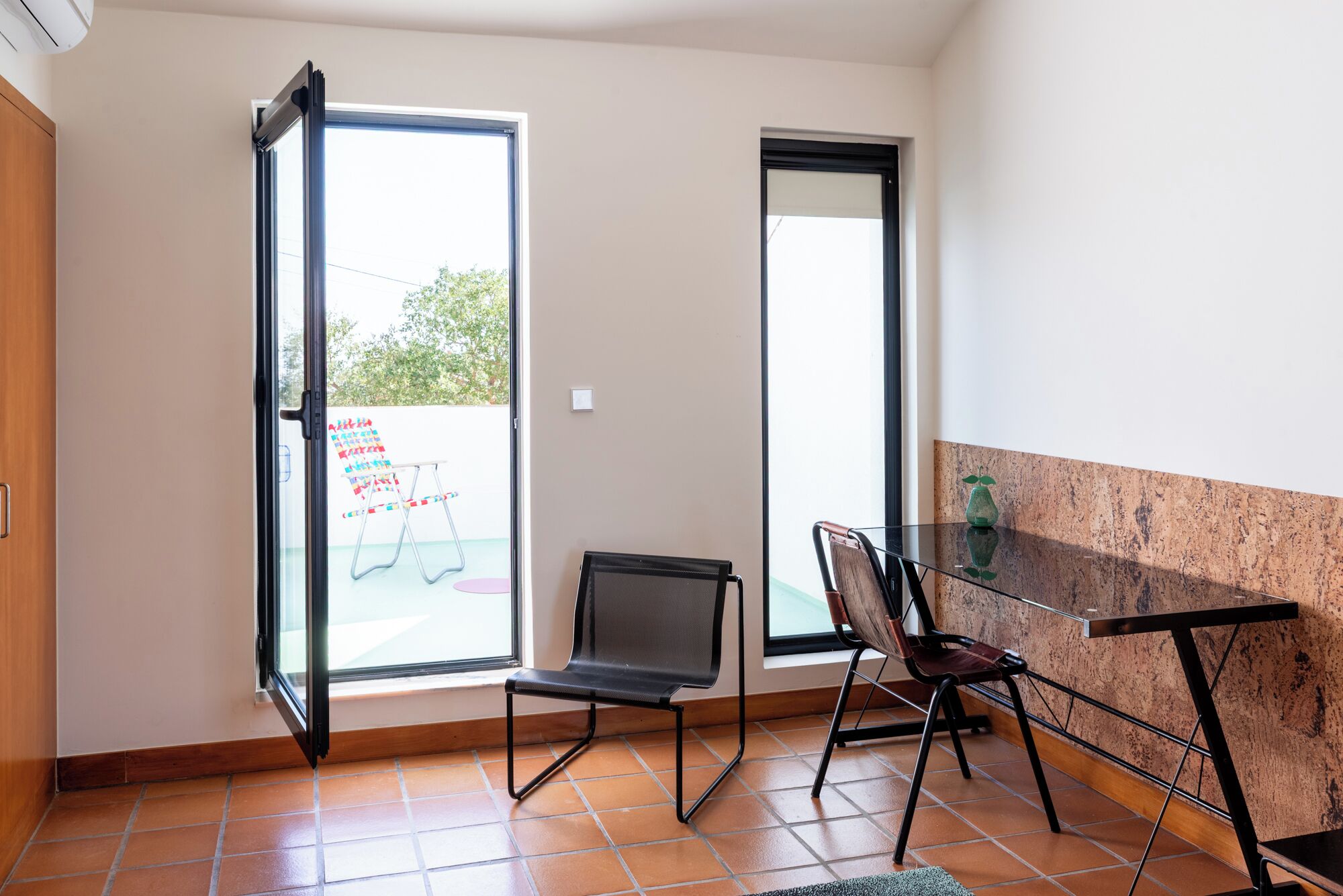 A room with a sliding glass door, a small table, a chair, and a view of the outside.