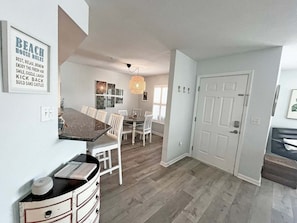A modern kitchen with a dining area, white cabinetry, and a chandelier. - Anastasia by the Sea 208A – Where Plans Meet Possibilities (St. Augustine)