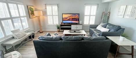 A modern living room with a sofa, a coffee table, a television, and a ceiling fan.
