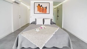 A modern bedroom with a large bed, a framed artwork above the bed, and a walk-in shower to the right. - Villa Carlota (Costa Adeje) (Costa Adeje)