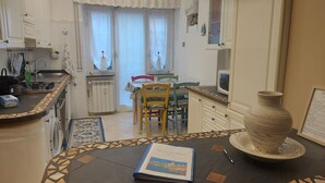 A kitchen with white cabinets, a dining table with chairs, a microwave, and a large vase on the counter.