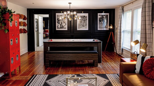 A room with a pool table, a red storage unit, and a sofa with a red pillow. - NEW Luxe Retro Sports Retreat~Walk to Stadiums (Raleigh)