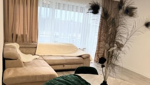 A modern living room with a sofa set, a round dining table, and a decorative vase with feathers.