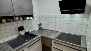 A modern kitchen with a black stove, white cabinets, and a grey countertop.