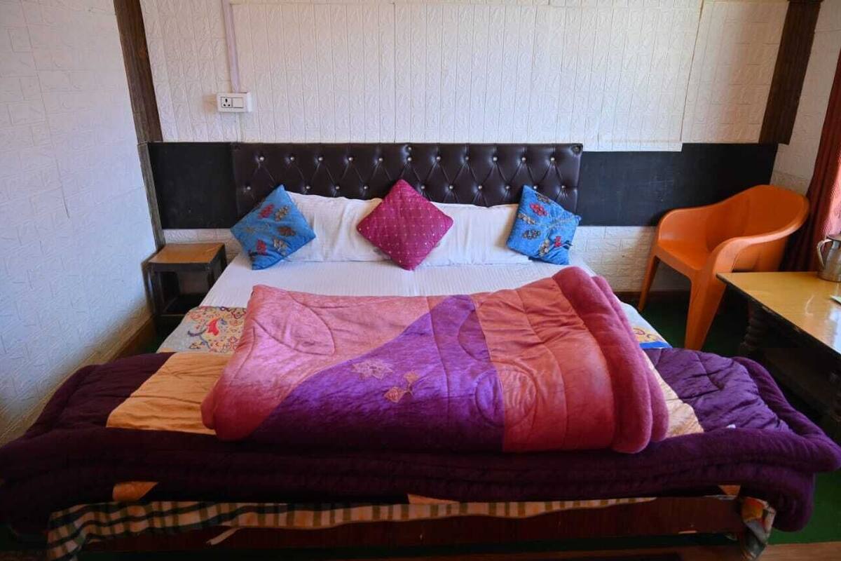 A bed with a quilt, pillows, and a blanket.
