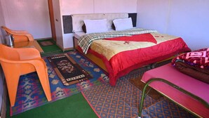 A small, compact room with a bed, a chair, and a table. - The Snow City Auli (Auli)