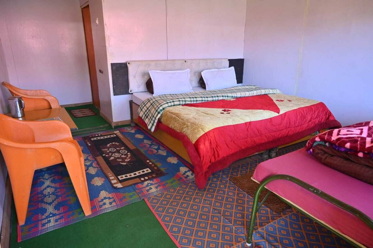 A small, compact room with a bed, a chair, and a table.