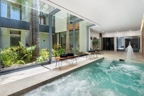 Ein moderner Innenpoolbereich mit Glaswänden, Sitzgelegenheiten und einem Wasserspiel.